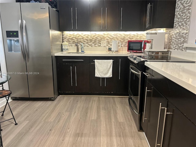 kitchen featuring decorative backsplash, sink, appliances with stainless steel finishes, and light hardwood / wood-style flooring