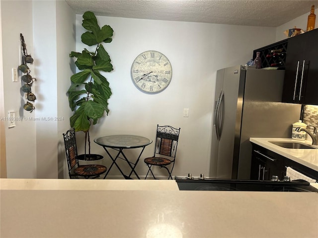 kitchen featuring a textured ceiling, stainless steel refrigerator, and sink