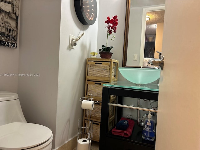 bathroom with a textured ceiling, toilet, and sink