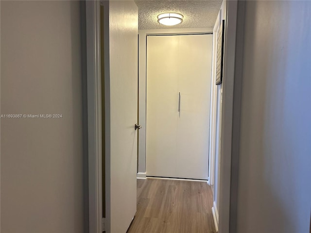 hallway featuring light wood-type flooring and a textured ceiling