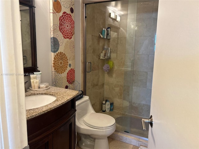 bathroom featuring tile patterned flooring, vanity, a shower with shower door, and toilet