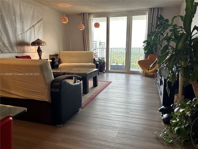 living room with hardwood / wood-style floors, floor to ceiling windows, and a textured ceiling