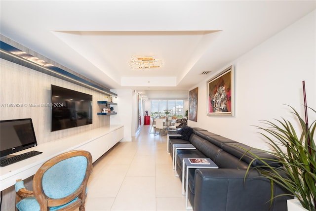 living room featuring a tray ceiling and light tile patterned floors