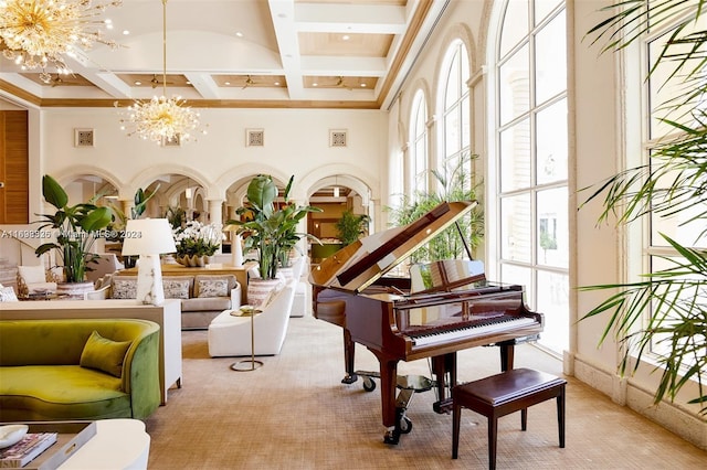 misc room with a towering ceiling, light colored carpet, an inviting chandelier, and coffered ceiling