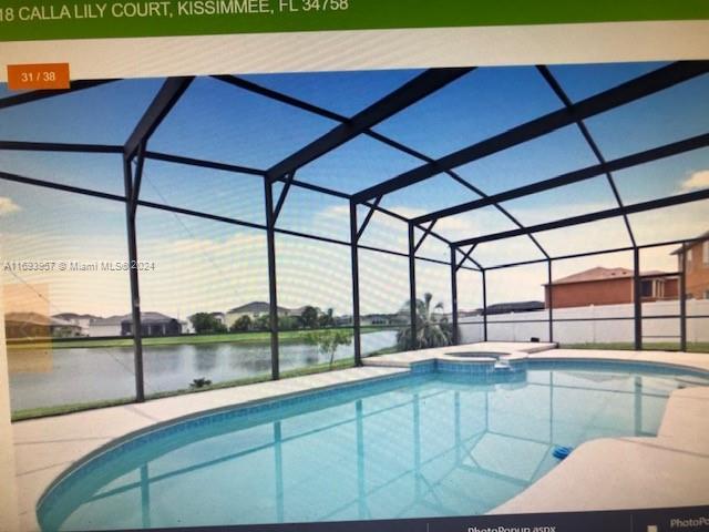 view of pool with a patio area, an in ground hot tub, a water view, and glass enclosure