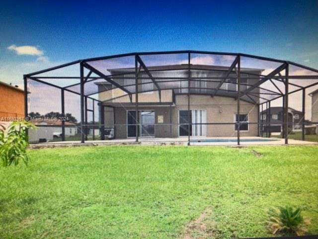 rear view of property with a yard and glass enclosure