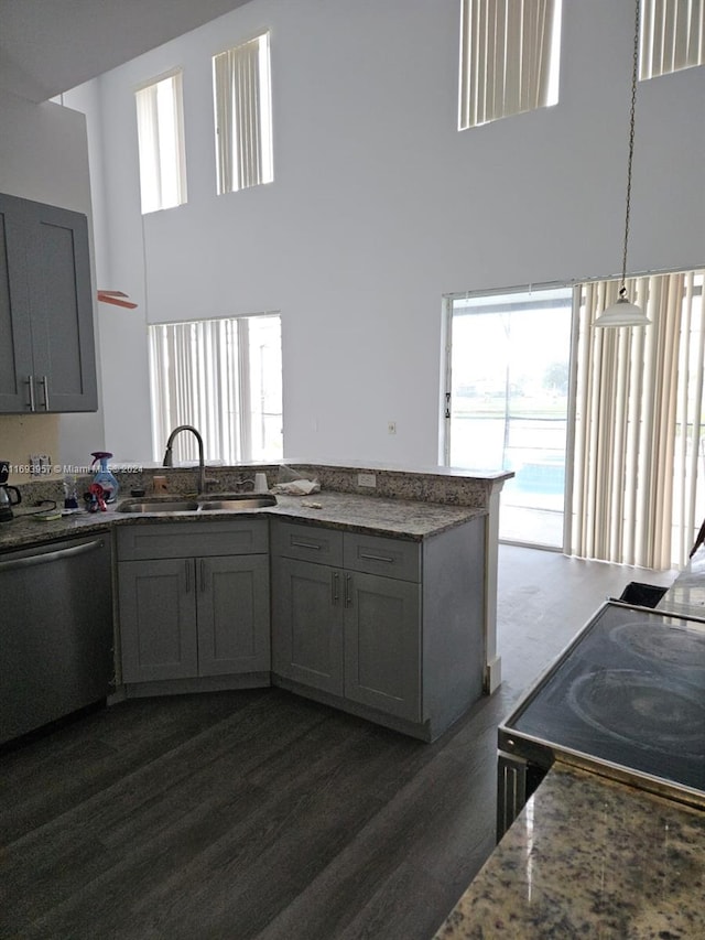 kitchen with stainless steel dishwasher, a healthy amount of sunlight, sink, and a high ceiling