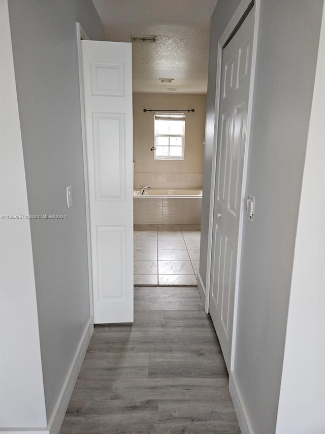 corridor with hardwood / wood-style floors and a textured ceiling