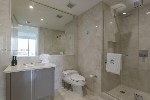 bathroom with vanity, toilet, tile walls, and a shower with shower door