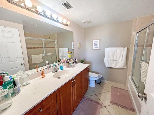 full bathroom featuring tile patterned flooring, bath / shower combo with glass door, a textured ceiling, toilet, and vanity