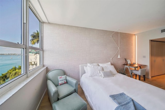 bedroom featuring hardwood / wood-style flooring and a water view