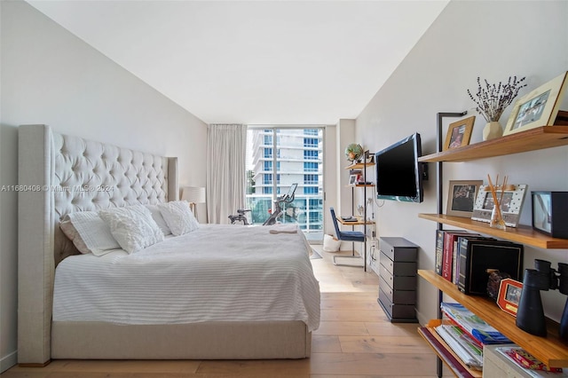 bedroom with a wall of windows and light wood-type flooring