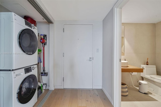 clothes washing area featuring stacked washer / dryer and light hardwood / wood-style flooring