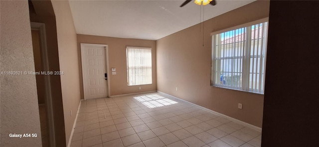 tiled empty room featuring a wealth of natural light and ceiling fan