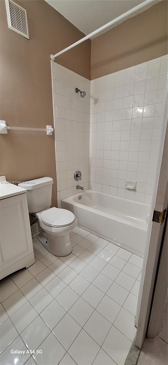 bathroom featuring tile patterned flooring, toilet, and tiled shower / bath