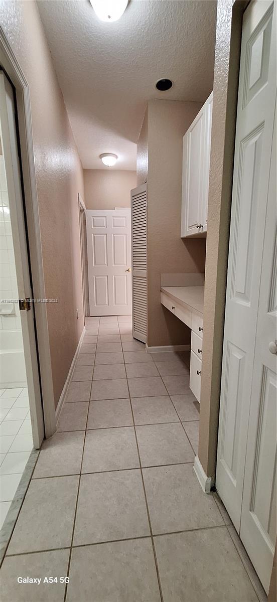 hall featuring light tile patterned floors and a textured ceiling