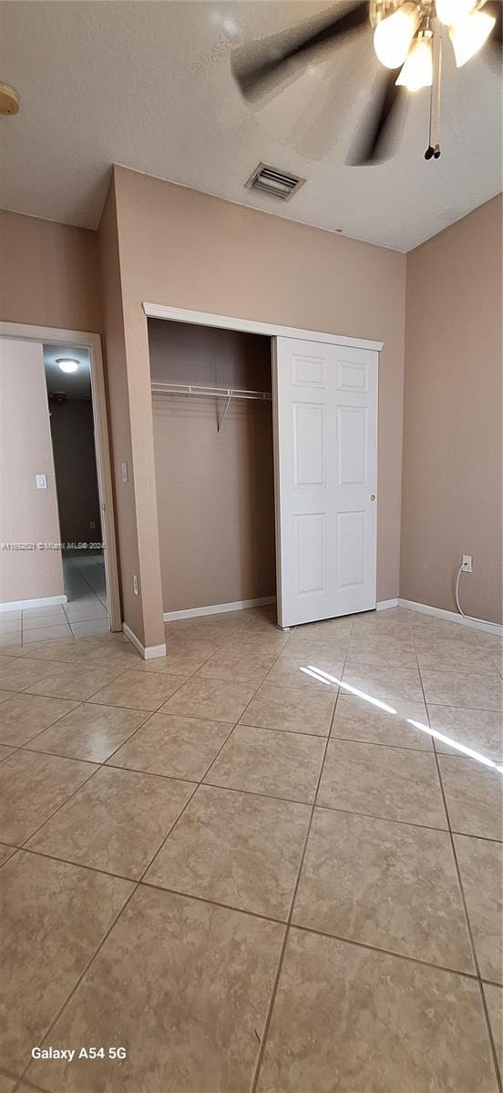 unfurnished bedroom with ceiling fan, light tile patterned flooring, and a closet