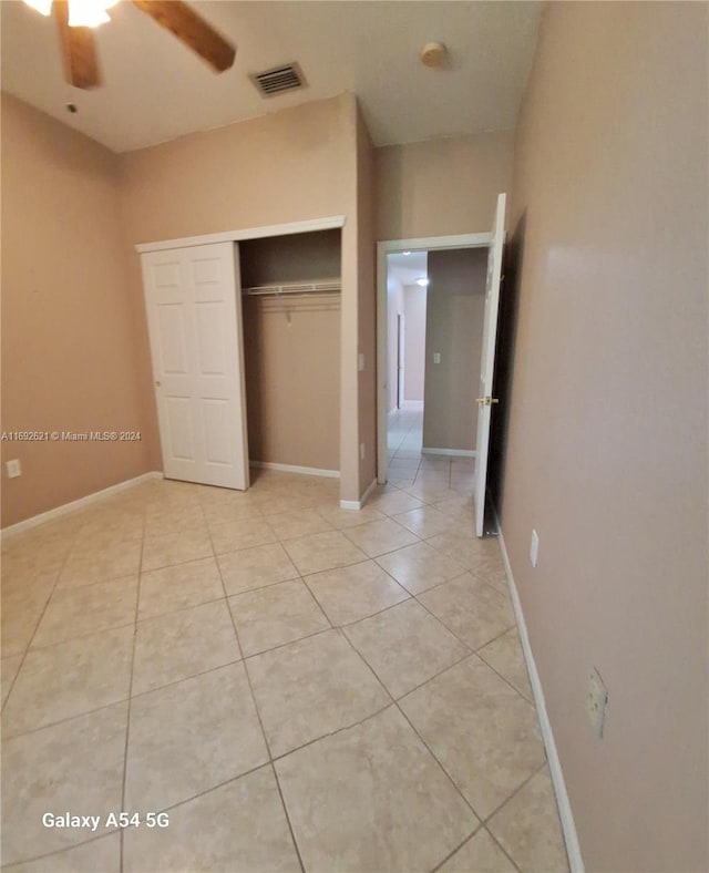 unfurnished bedroom featuring ceiling fan, light tile patterned floors, and a closet