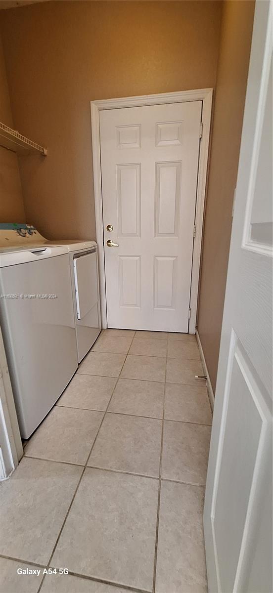 laundry room featuring separate washer and dryer and light tile patterned floors