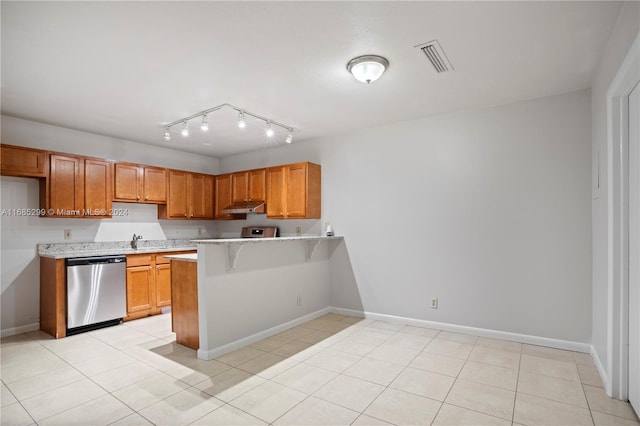 kitchen featuring dishwasher, a kitchen bar, light tile patterned flooring, and sink