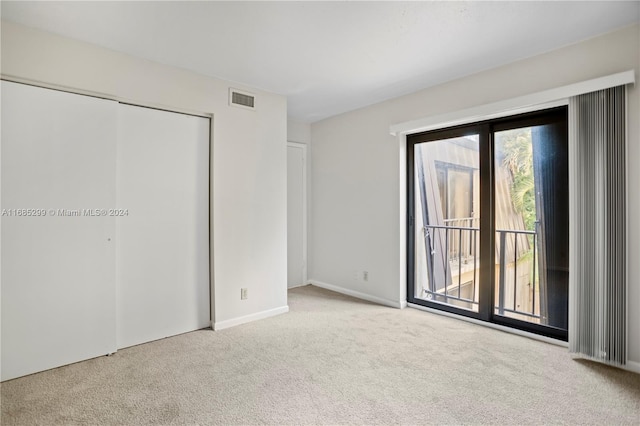 unfurnished bedroom with access to exterior, light colored carpet, and a closet