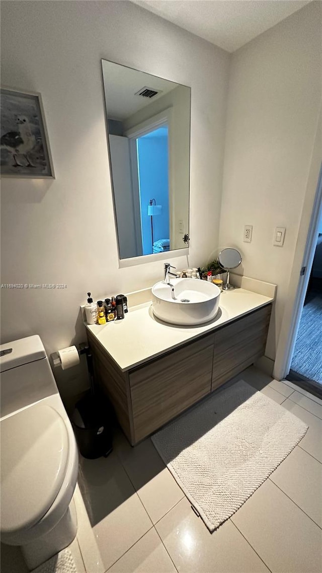 bathroom with toilet, vanity, and tile patterned floors