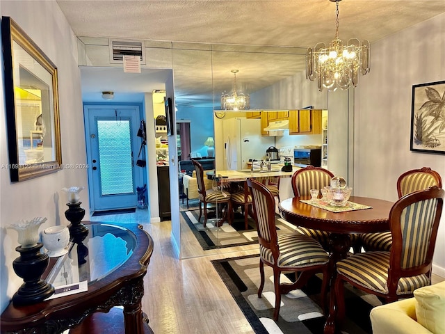 dining room featuring light wood-type flooring, a textured ceiling, and a chandelier