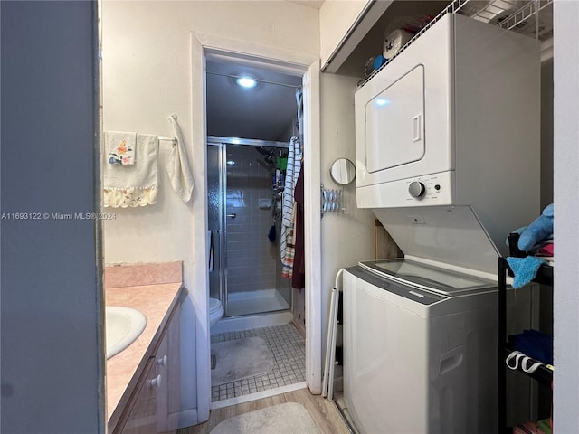 clothes washing area featuring stacked washer / dryer, sink, and light tile patterned flooring