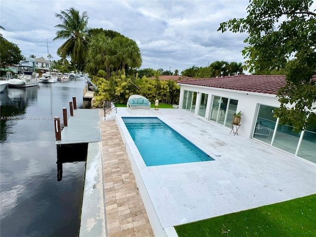 view of swimming pool featuring a boat dock, a water view, and a patio area