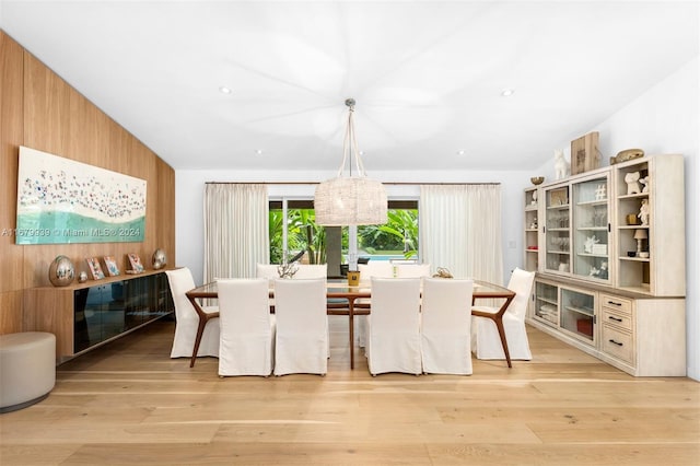 dining space with a chandelier, light hardwood / wood-style flooring, and lofted ceiling