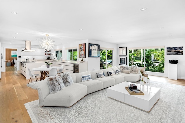 living room featuring light wood-type flooring, a chandelier, and wine cooler