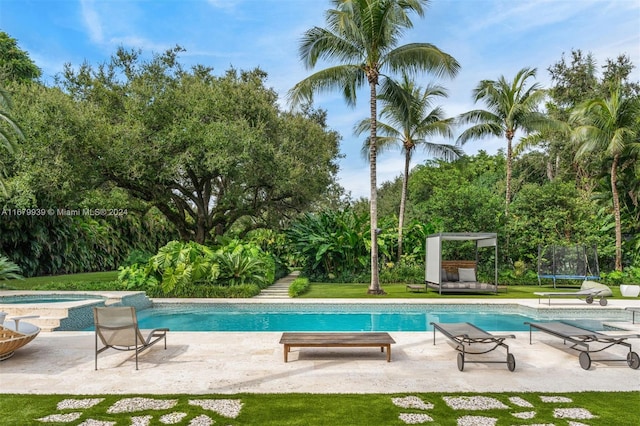 view of swimming pool featuring a patio, an in ground hot tub, and a trampoline