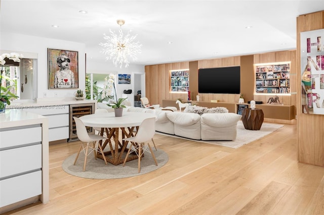 dining area with an inviting chandelier, wine cooler, and light hardwood / wood-style floors