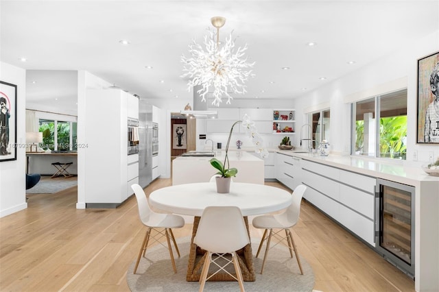 dining room with sink, light wood-type flooring, and wine cooler