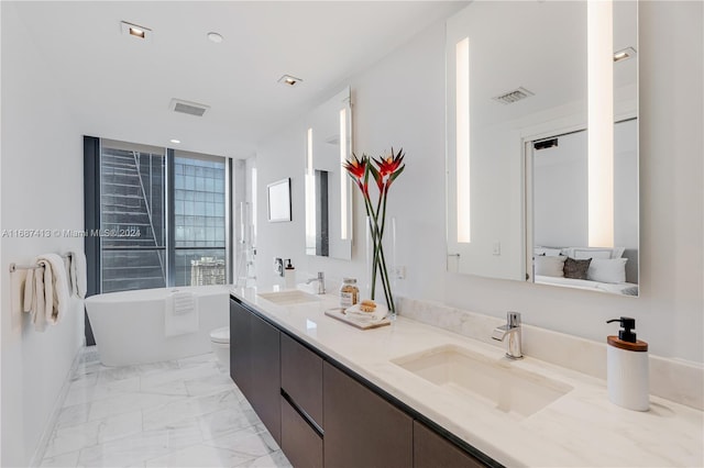 bathroom with vanity, a tub to relax in, and toilet