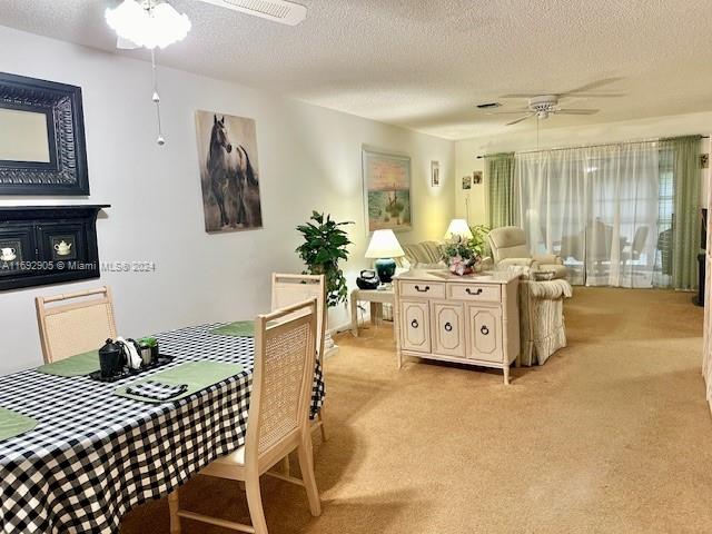 carpeted dining space with ceiling fan and a textured ceiling