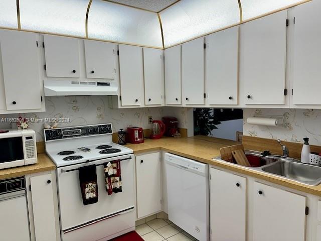 kitchen with white cabinets, white appliances, sink, and light tile patterned floors