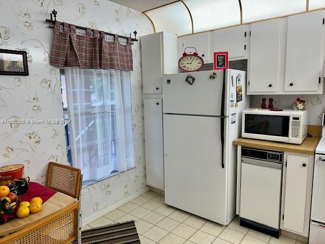 kitchen with light tile patterned floors, white cabinets, and white appliances