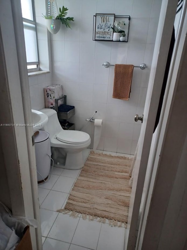 bathroom featuring tile patterned flooring, toilet, and tile walls