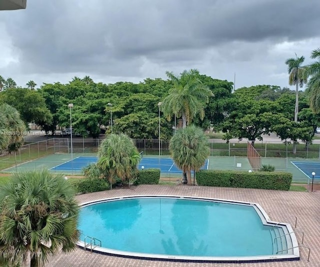 view of pool with tennis court