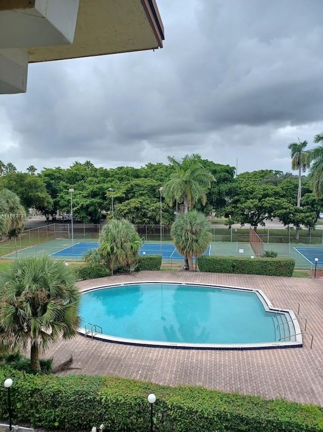 view of swimming pool featuring tennis court