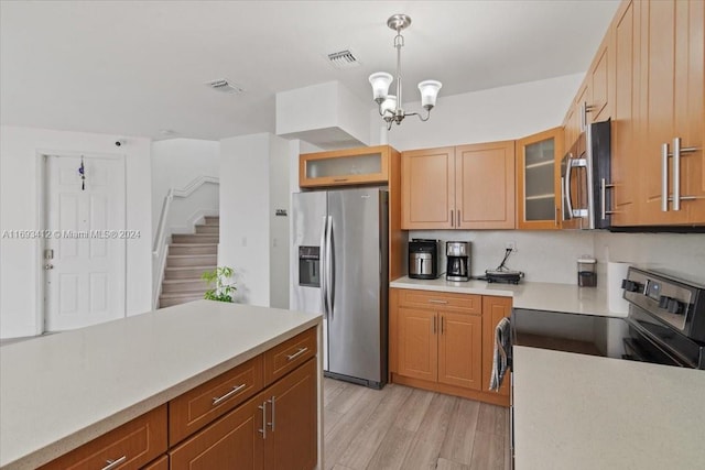 kitchen with appliances with stainless steel finishes, light wood-type flooring, an inviting chandelier, and hanging light fixtures