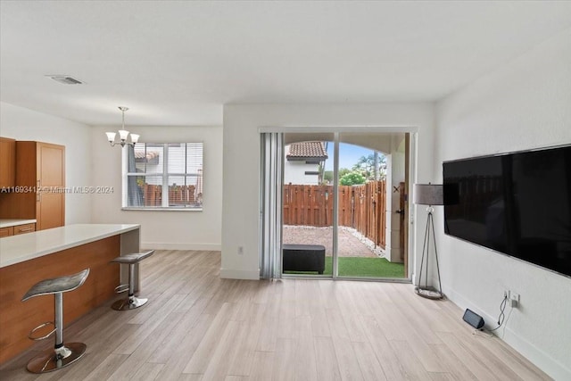 living room with light hardwood / wood-style floors, an inviting chandelier, and a wealth of natural light