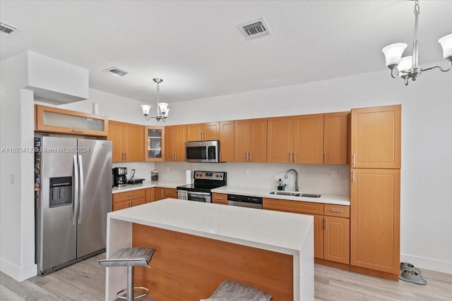 kitchen featuring an inviting chandelier, sink, light wood-type flooring, decorative light fixtures, and stainless steel appliances