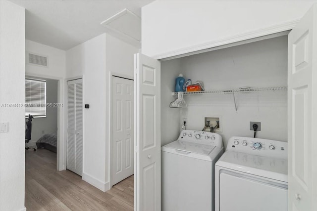 laundry room with light hardwood / wood-style floors and washing machine and clothes dryer