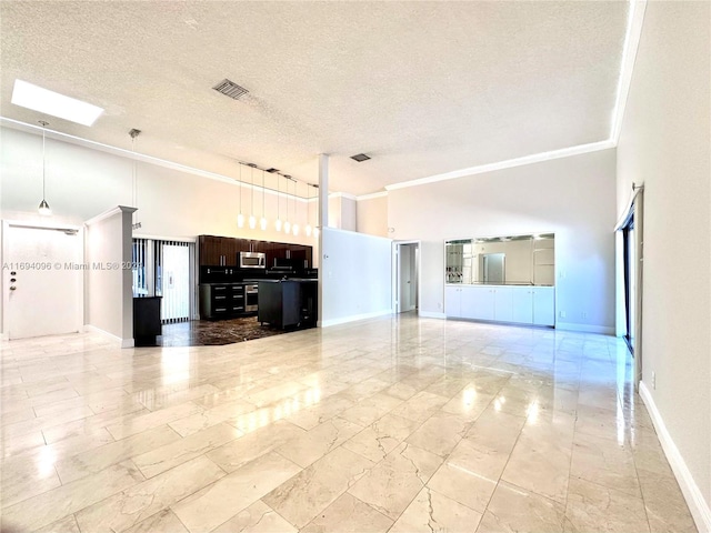 unfurnished living room with a textured ceiling, a skylight, a high ceiling, and ornamental molding