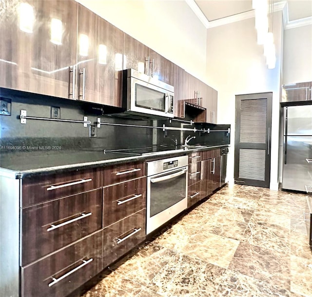 kitchen with dark brown cabinets, stainless steel appliances, hanging light fixtures, and crown molding