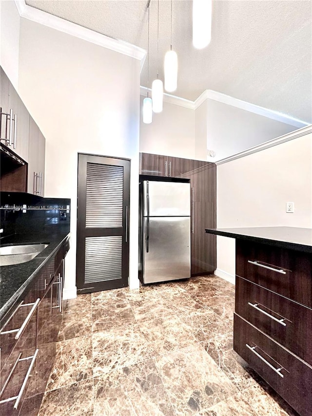 kitchen with sink, hanging light fixtures, stainless steel fridge, crown molding, and a textured ceiling