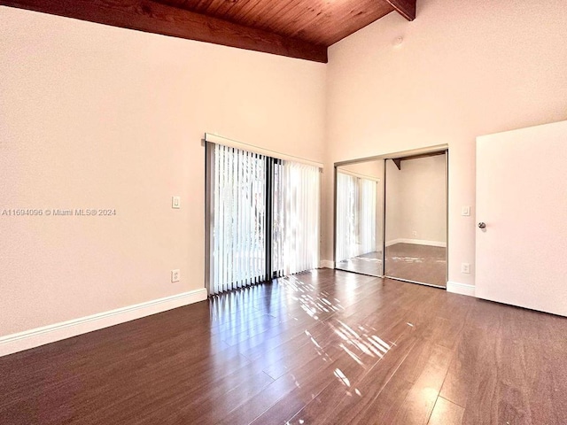 unfurnished bedroom featuring wood ceiling, dark wood-type flooring, beam ceiling, high vaulted ceiling, and a closet