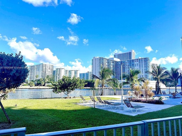 surrounding community with a patio area, a yard, and a water view